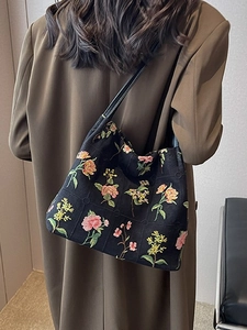 Stylish black canvas bucket bag featuring vibrant floral embroidery and leather shoulder strap