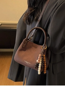 Braune Retro-Eimertasche aus Wildleder mit Tragegriff und Schultergurt am Model