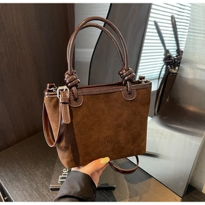 Detailed view of the dark brown suede tote bag with knotted handles and embossed floral logo