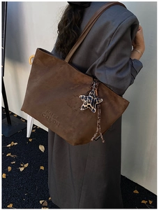 Detail of dark brown suede tote bag featuring embossed logo and leopard star charm pendant