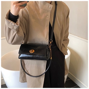 Vue détaillée du sac bandoulière en cuir brillant noir avec boucle dorée circulaire élégante