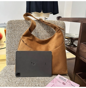 Sac hobo en daim marron posé à côté d'un iPad pour montrer sa grande capacité