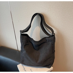 Dettaglio della borsa hobo in tela nera con tasca laterale e tracolla ampia regolabile