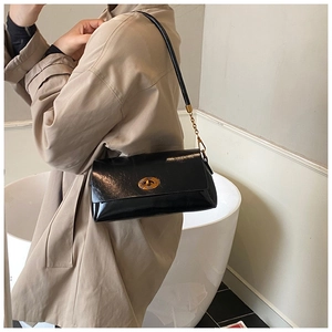 Détail d'un sac à bandoulière en cuir noir avec fermoir doré vintage et chaîne élégante