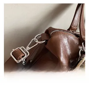 Macro detail of brown tote bag with silver metal swivel hook and braided strap accent