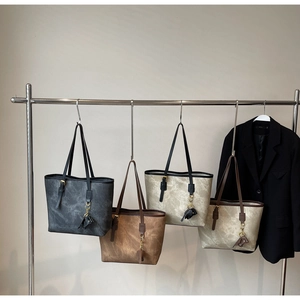 Selection of faux leather tote bags with marble texture hanging on a metal display rack
