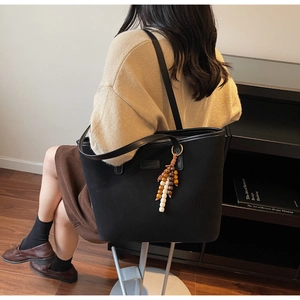 Close-up of black matte tote bag with bohemian wooden bead charm and zipper detail