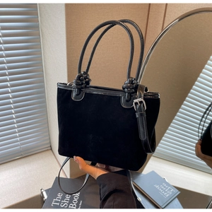 Detail of black velvet bucket bag with decorative rope handles and knotted design