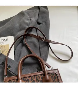 Detail shot of the adjustable brown shoulder strap and leopard print square handbag texture