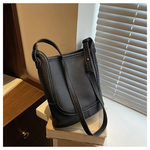 Detail of black lychee grain leather bucket bag showing fine stitching and strap