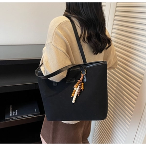 Detail of black canvas tote bag with multi-color wooden bead tassel for casual daily commute