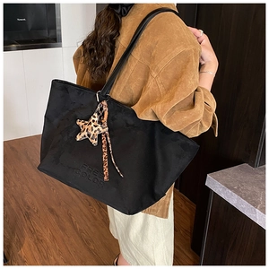 Detail of black suede tote bag featuring Free Color embossing and leopard print charm