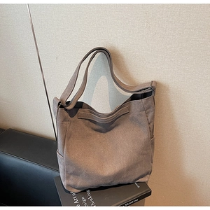 Dettaglio di una grande borsa tote in tela con tracolla regolabile appoggiata su libri
