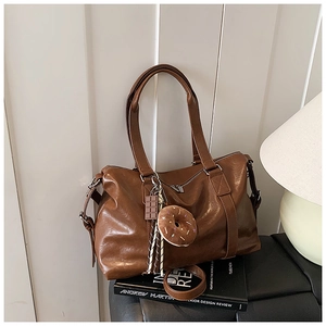 Detail of a brown vintage tote bag with chocolate and donut charms on a leather seat