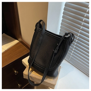 Close-up of black lychee grain leather bucket bag with elegant drawstring detail and strap