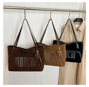 Detailed display of large suede tote bags in three colors with embossed MOACRI logo
