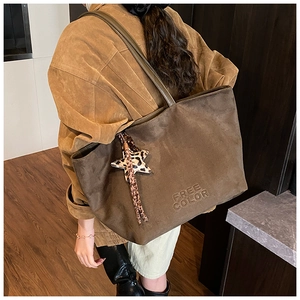 Detail view of brown suede tote bag with embossed letters and leopard star charm