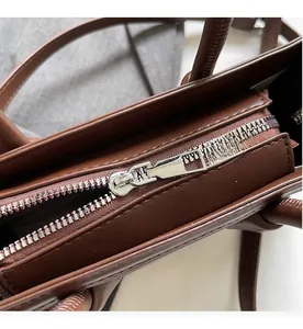 Close-up of the smooth silver metal zipper and stitching on the brown leather handbag
