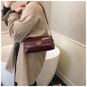 Détail du sac en cuir verni bordeaux avec fermoir rotatif doré et finition brillante