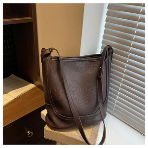 Detail of dark brown lychee leather texture on a vintage bucket bag with adjustable strap