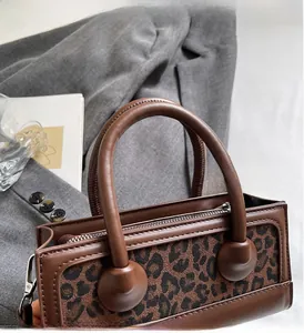 Detail of leopard print handbag showing sturdy leather handle and metal hardware