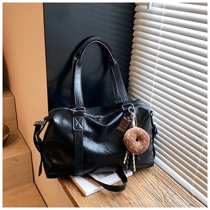 Detail of a black leather tote bag with chocolate and donut charms in stylish light