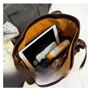 Macro view of large brown suede tote bag interior with bright yellow lining and pocket
