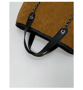 Detail showing high-quality brown suede fabric with black leather trim and silver chain