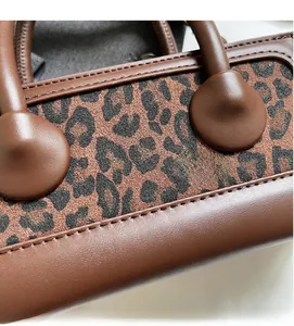 Detail of leopard print patchwork and precision stitching on brown leather handbag