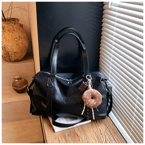 Close-up of black matte tote bag featuring cute plush donut and chocolate charms on side