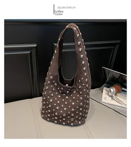 Dettaglio borsa hobo in pelle scamosciata marrone con borchie su divano elegante