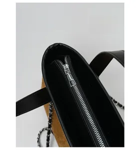 Close-up of suede tote bag with metal zipper detail and smooth leather stitching