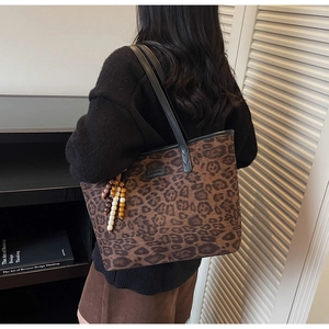 Detail of vintage leopard print tote bag with beaded charm on shoulder of a model