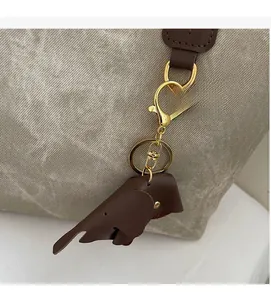 Detailed view of the elephant-shaped leather bag charm with gold hardware on a tote