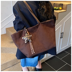 Detail of dark brown matte leather tote bag featuring leopard star charm and tassel