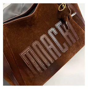 Detail of brown suede tote with MARCH embroidery and a cute elephant charm