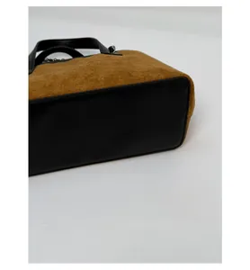 Detail view of the reinforced black leather base on the brown faux suede handbag