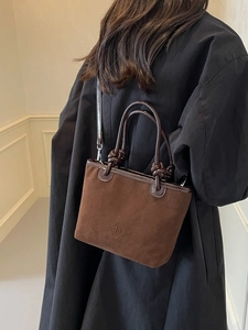 Brown suede tote bag with flower embossed logo and leather handle on a model