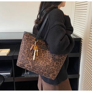 Detail of leopard print tote bag with stylish beaded tassel charm and black leather strap
