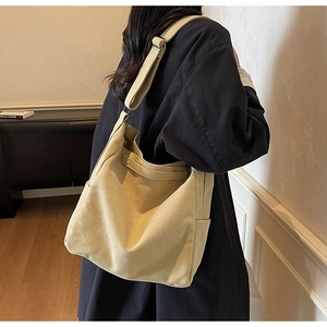 Dettaglio di una borsa a tracolla in tela beige con ampia tracolla e consistenza morbida