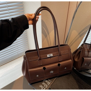 Detail of dark brown tote bag featuring silver buckles and multiple front flap pockets