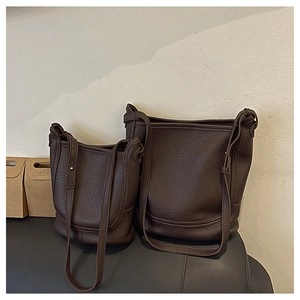 Two brown lychee leather bucket bags in different sizes with long shoulder straps