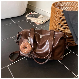 Detail view of large dark brown PU leather tote bag with glossy finish and cute charms