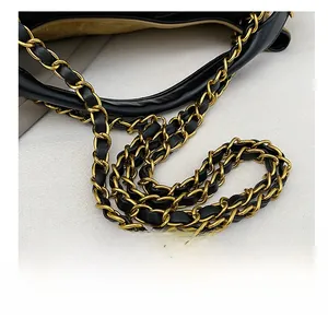Detail shot of premium black leather bag featuring a gold chain strap with fine texture