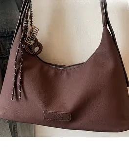 Detail of dark brown leather texture with an embossed logo tag and unique metal accessories