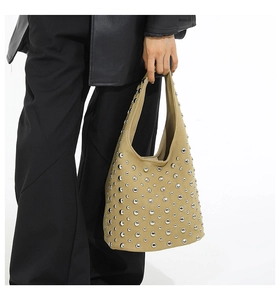 Dettaglio della borsa tote kaki con borchie in metallo argentato tenuta da una modella