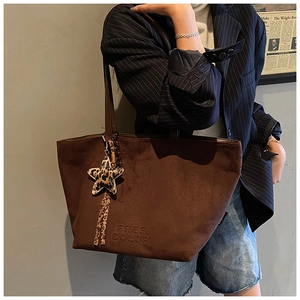 Detail of dark brown suede tote bag with FREE COLOR embossing and leopard star charm