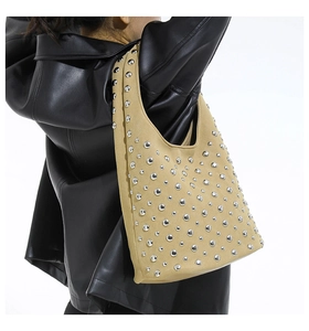 Dettaglio della borsa tote in pelle scamosciata beige con borchie e giacca di pelle