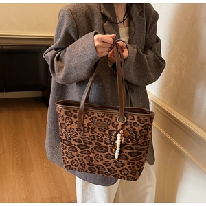 Detail of leopard print tote bag featuring matte texture and decorative beaded keychain