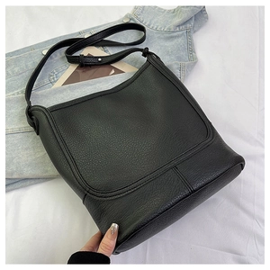 Close-up of black lychee grain leather bucket bag styled on a denim jacket background